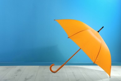 Image of Beautiful orange umbrella near blue wall. Space for text