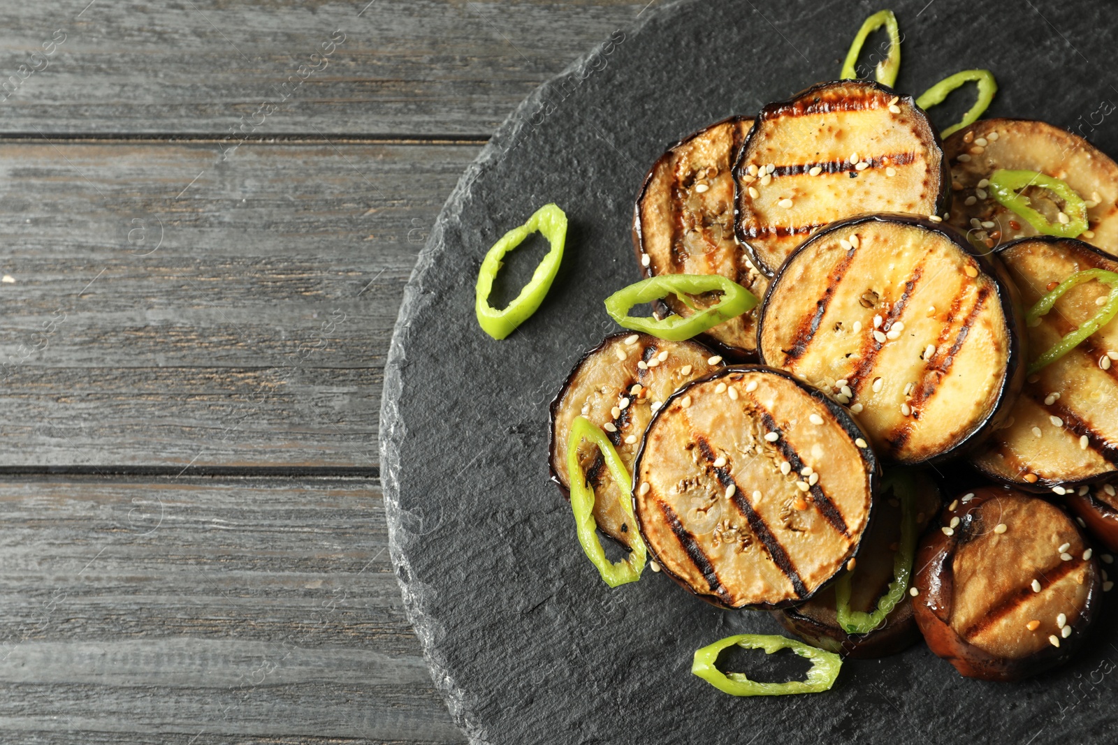 Photo of Slate plate with fried eggplant slices on wooden table, top view. Space for text