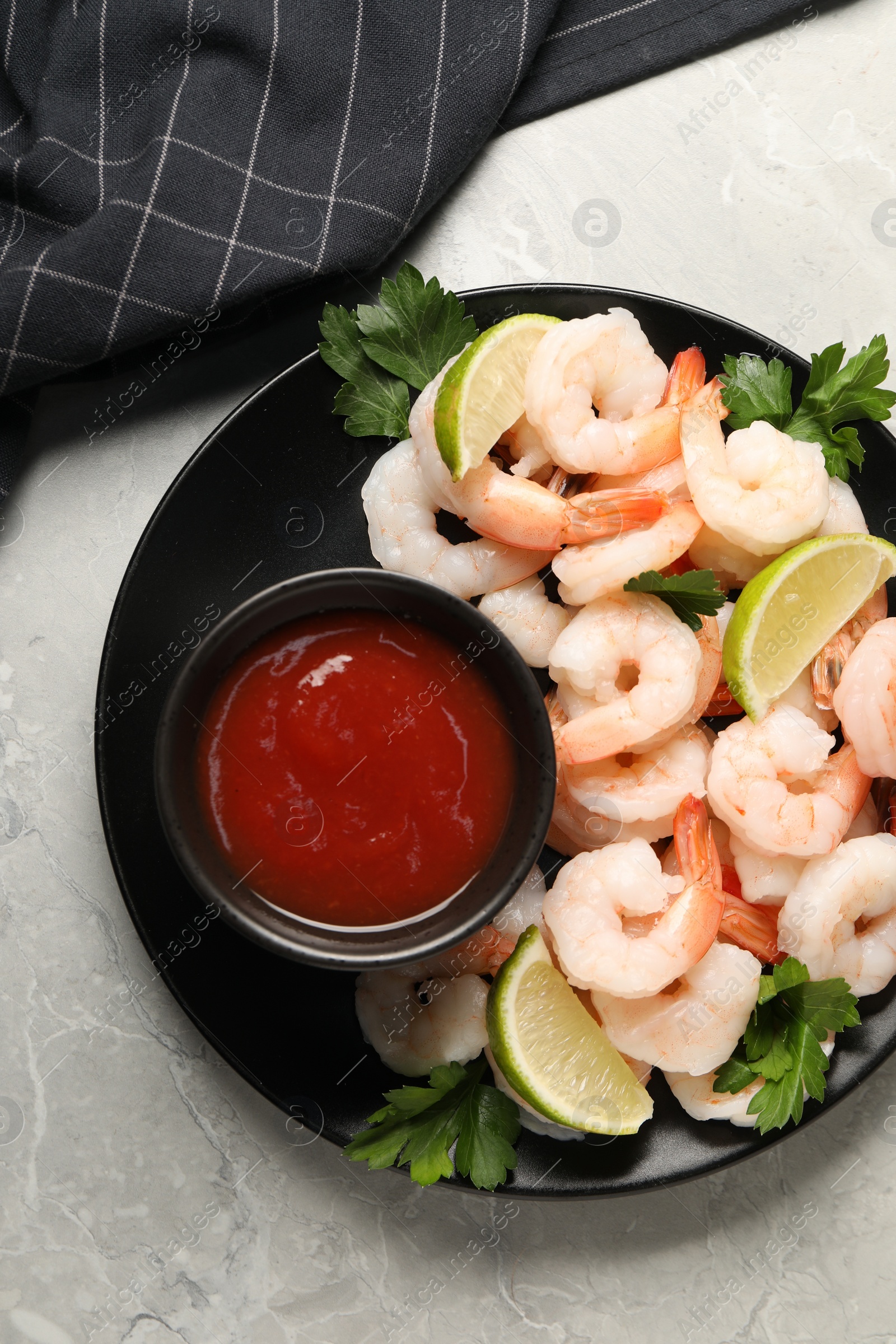 Photo of Tasty boiled shrimps with cocktail sauce, parsley and lime on light grey table, top view