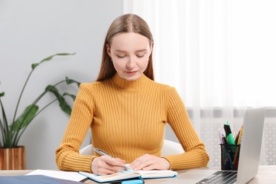 Photo of Woman taking notes at table in office