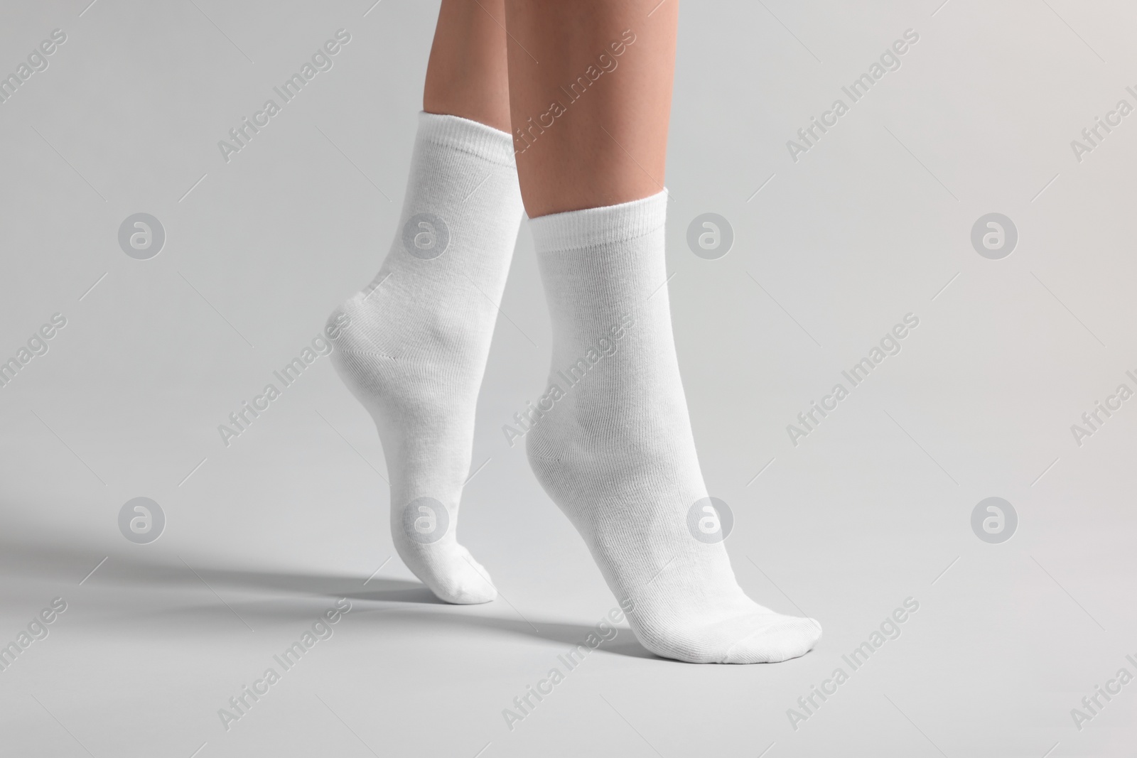 Photo of Woman in stylish white socks on light grey background, closeup