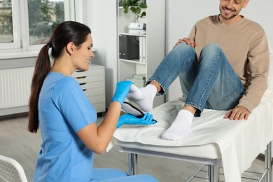 Beautiful female orthopedist fitting insole to patient's foot in hospital