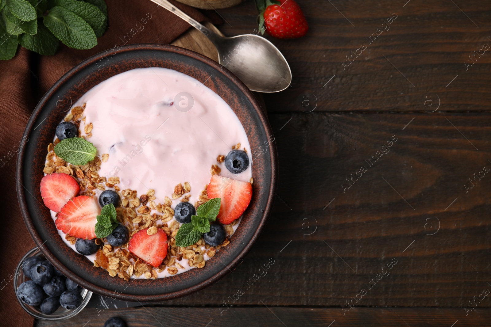 Photo of Bowl with yogurt, berries and granola on wooden table, flat lay. Space for text