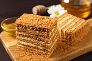 Delicious layered honey cake served on wooden board, closeup