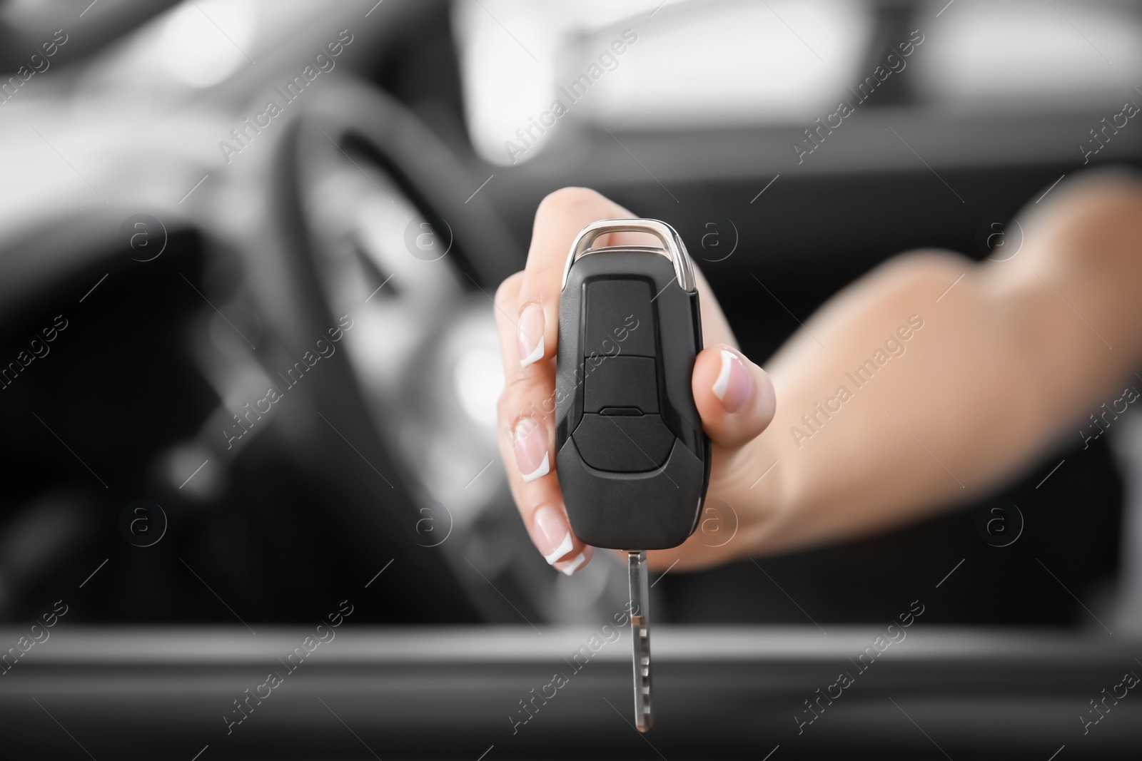 Photo of Young woman with key sitting in driver's seat of new car, closeup