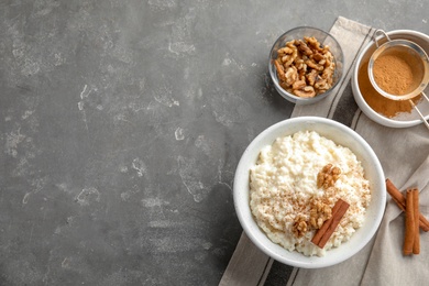 Photo of Creamy rice pudding with cinnamon and walnuts in bowl served on grey table, top view. Space for text