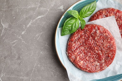 Raw meat cutlets for burger on marble table, top view. Space for text