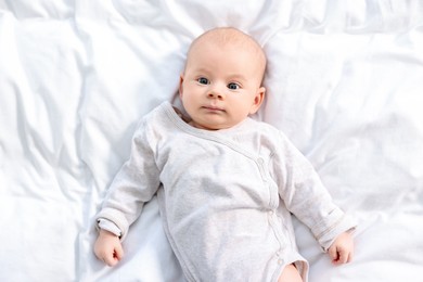 Cute little baby lying on white sheets, top view