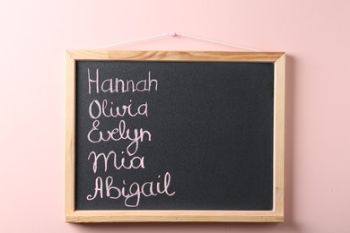 Blackboard with baby names hanging on pink wall