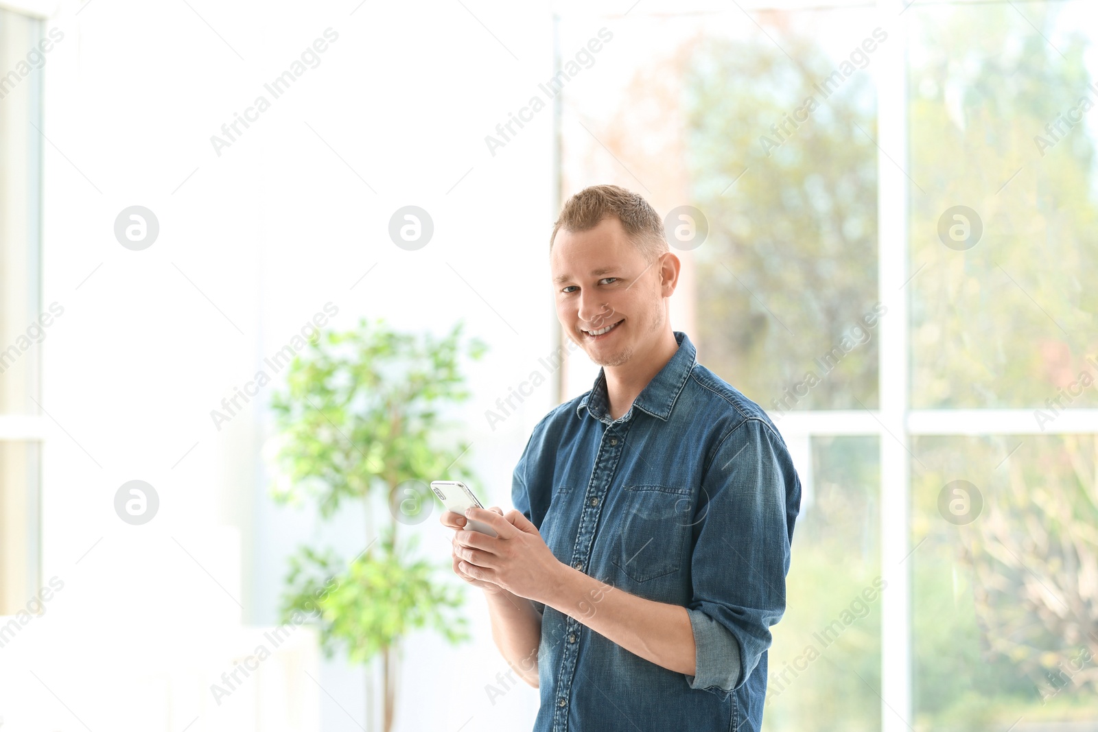 Photo of Portrait of handsome man with mobile phone, indoors