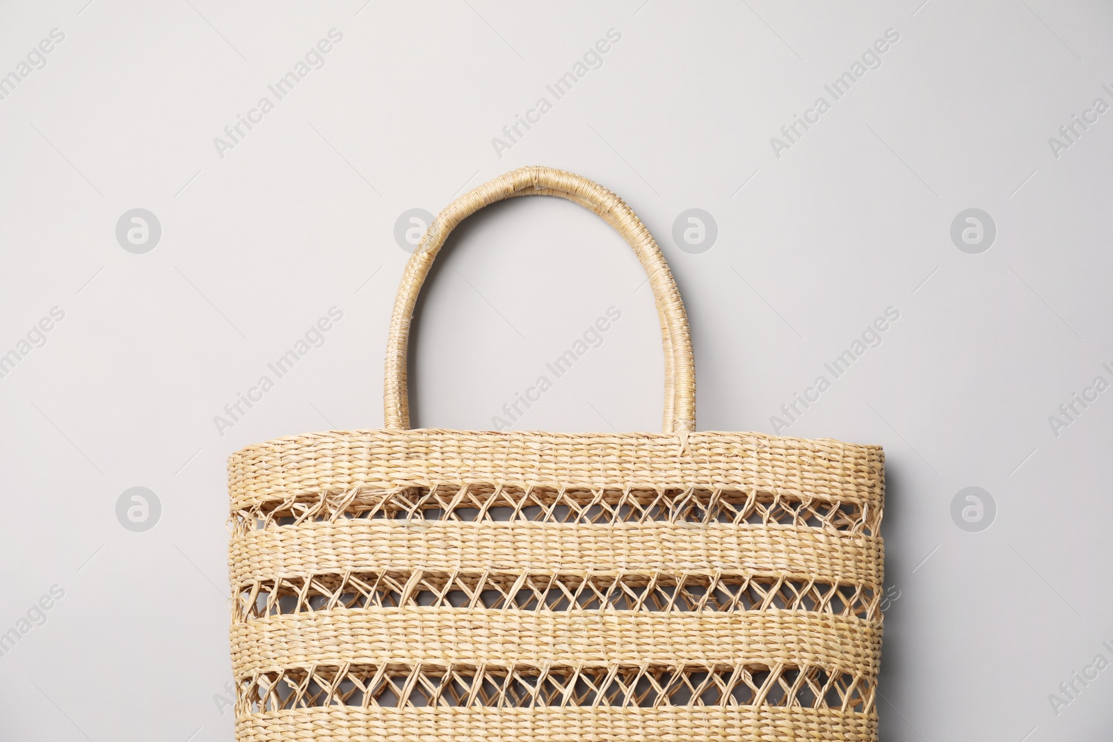 Photo of Stylish straw bag on grey background, top view. Summer accessory