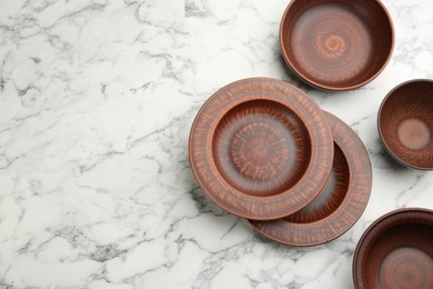 Set of clay dishes on white marble table, flat lay. Space for text