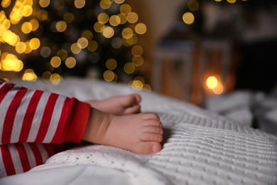 Photo of Baby in Christmas pajamas sleeping on bed indoors, closeup