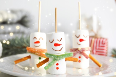 Image of Funny snowmen made of marshmallows on plate, closeup. Bokeh effect 