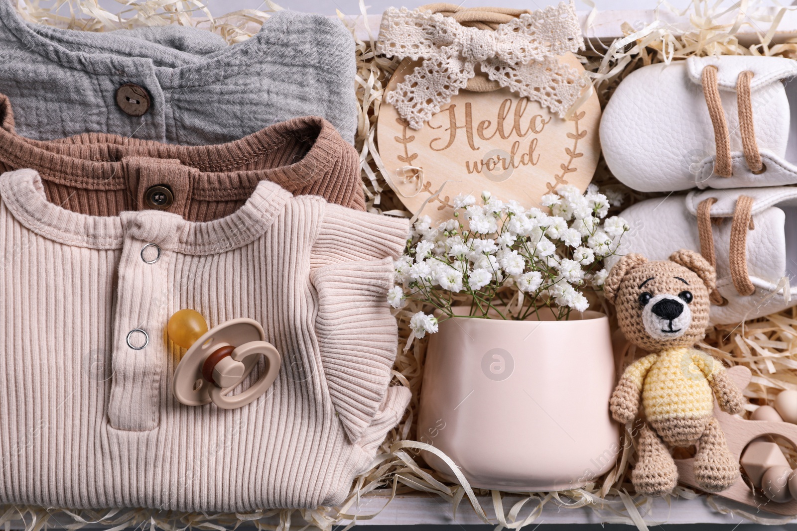 Photo of Baby clothes, booties and toys in box, top view