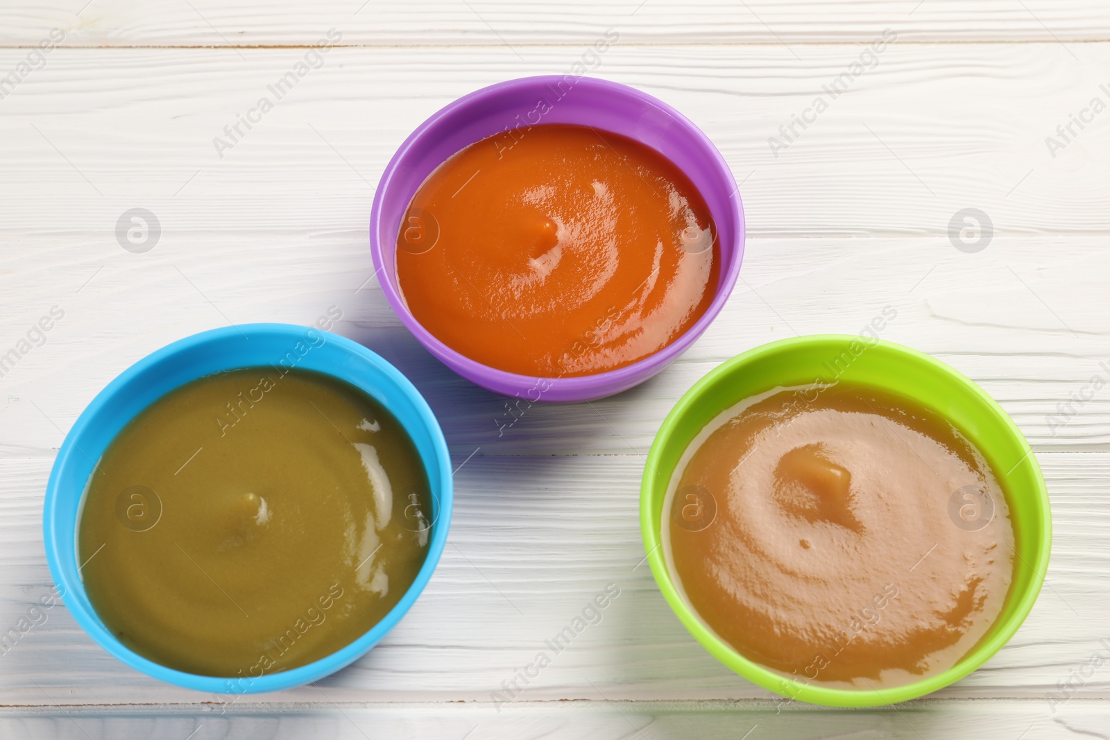 Photo of Baby food. Different purees in bowls on white wooden table