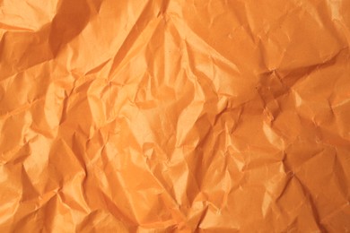 Sheet of crumpled orange paper as background, top view