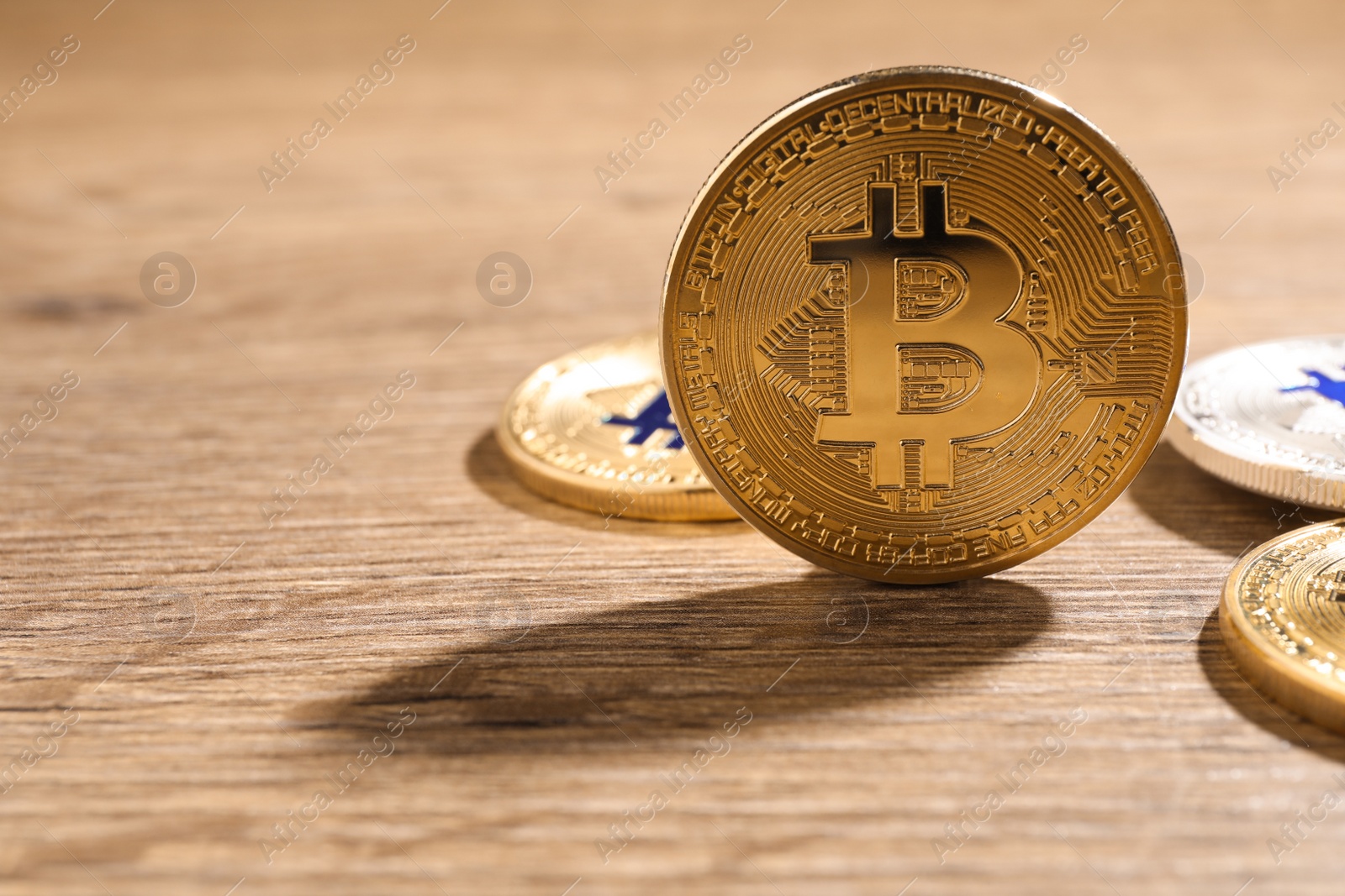 Photo of Shiny bitcoins on wooden background, space for text. Digital currency