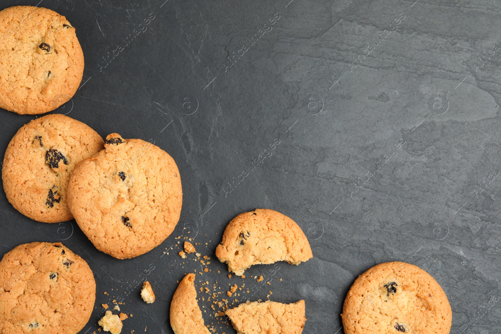 Photo of Delicious cookies with raisins on black table, flat lay. Space for text