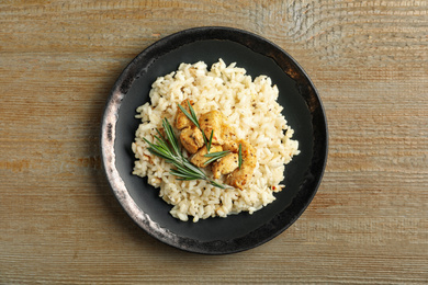 Delicious risotto with chicken on wooden table, top view