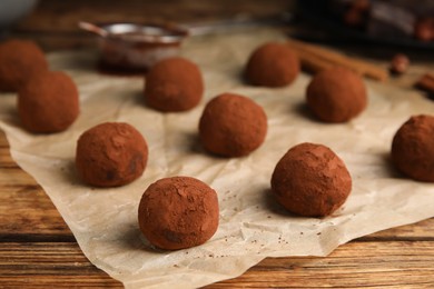 Photo of Delicious chocolate truffles powdered with cocoa on wooden table, closeup