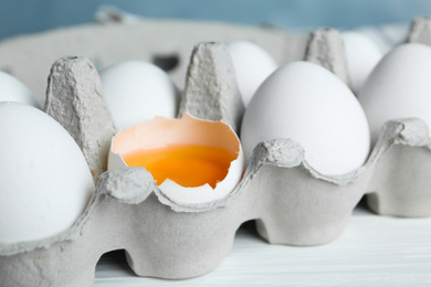 Photo of Fresh raw chicken eggs in box on white table, closeup