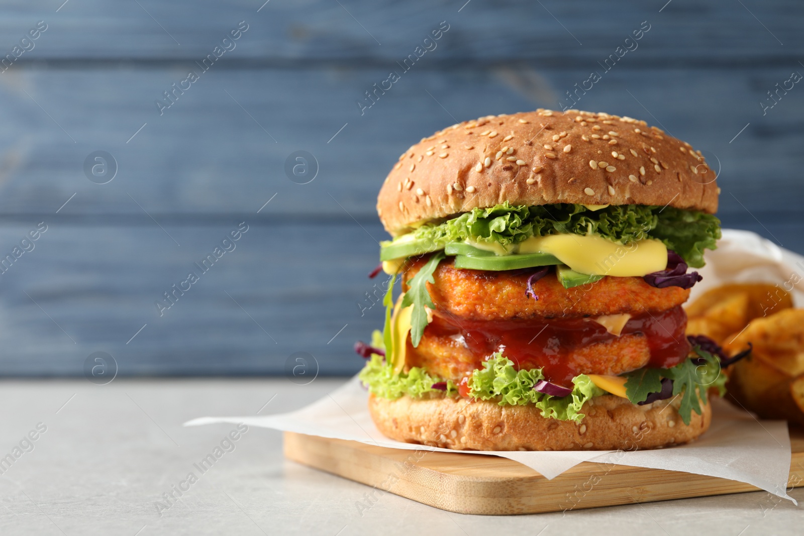 Photo of Vegan burger with carrot patties served on table against color background. Space for text