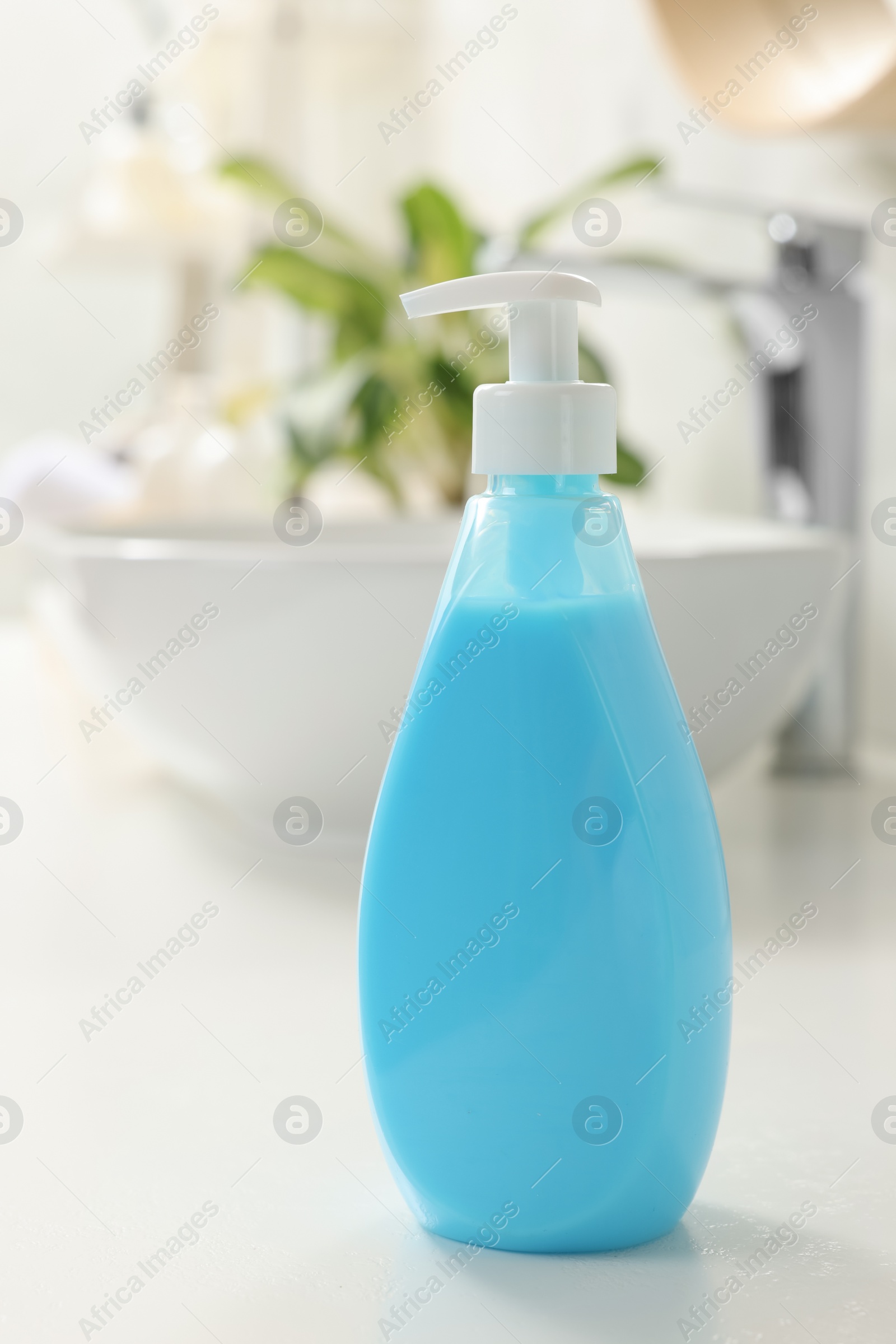 Photo of Dispenser of liquid soap on white table in bathroom