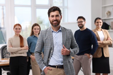 Portrait of happy businessman and his team in office