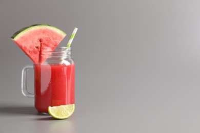 Tasty summer watermelon drink with lime in glass mason jar on grey background. Space for text