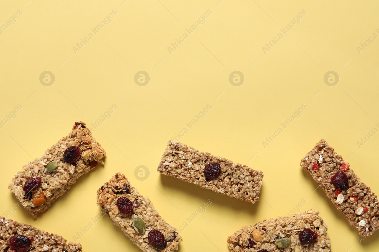 Photo of Tasty granola bars on yellow background, flat lay. Space for text