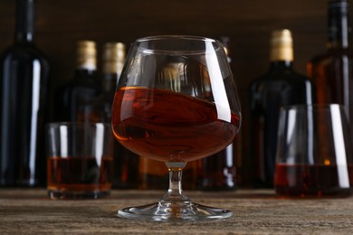 Different delicious liqueurs in glasses and bottles on wooden table