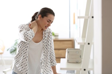 Photo of Woman suffering from neck pain in office. Bad posture problem