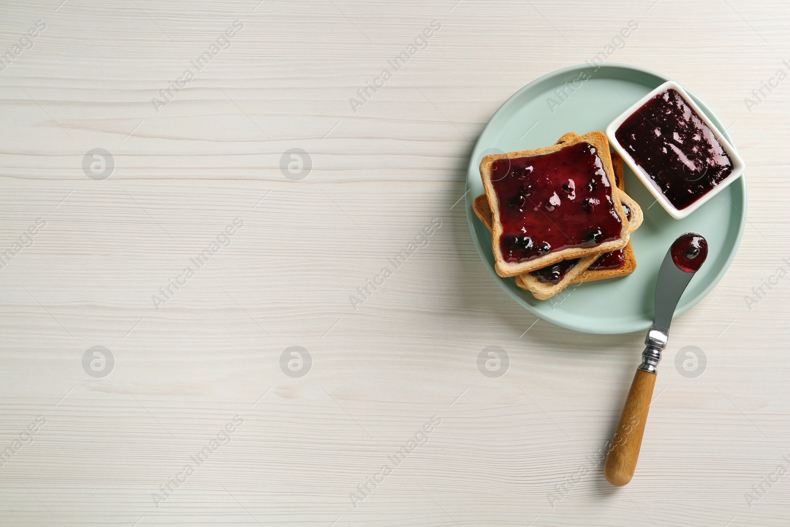 Photo of Delicious toasts with jam served on white wooden table, top view. Space for text