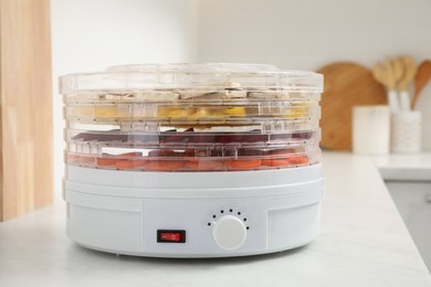 Modern dehydrator machine with vegetables in kitchen
