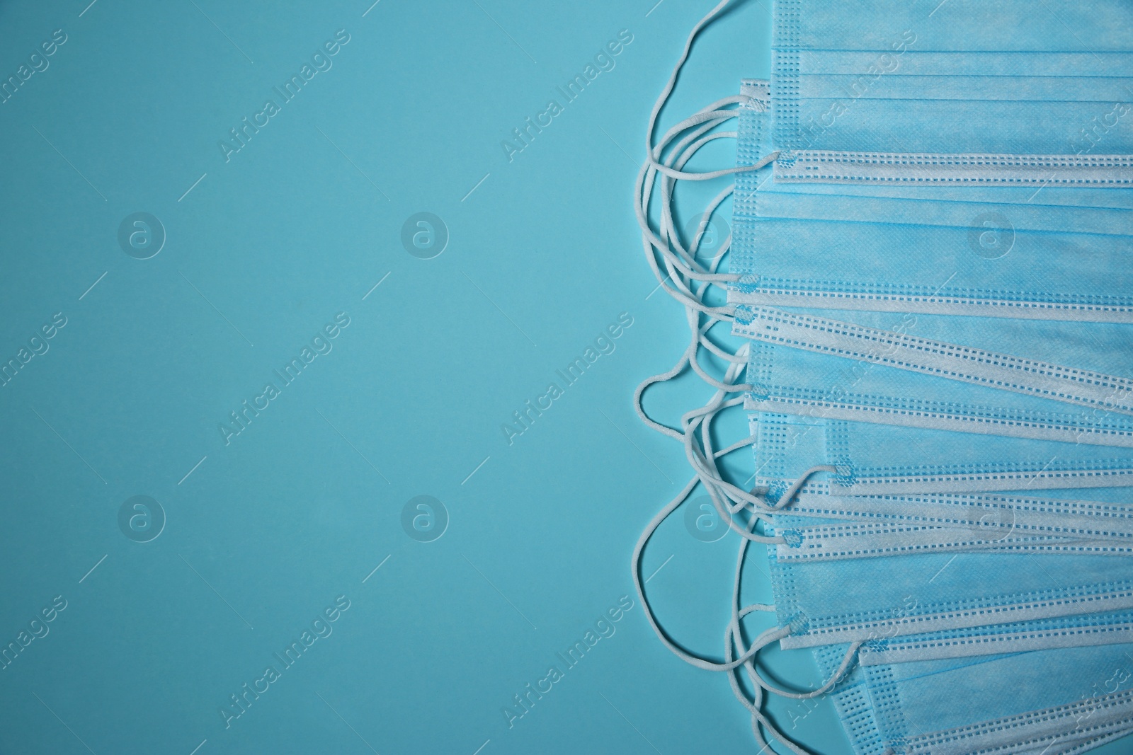 Photo of Disposable face masks on light blue background, flat lay with space for text. Protective measures during coronavirus quarantine