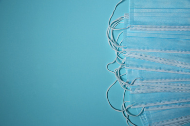 Photo of Disposable face masks on light blue background, flat lay with space for text. Protective measures during coronavirus quarantine