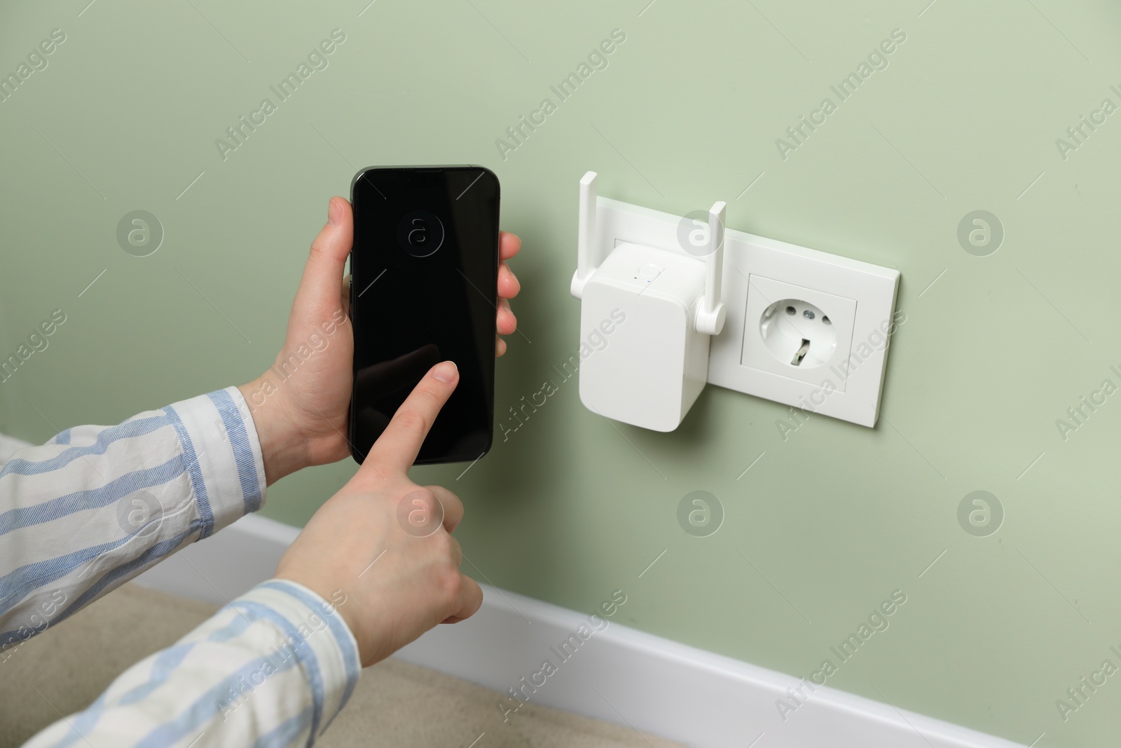 Photo of Woman using smartphone for wireless Wi-Fi repeater indoors, closeup