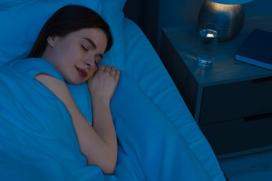 Beautiful young woman sleeping in bed at night