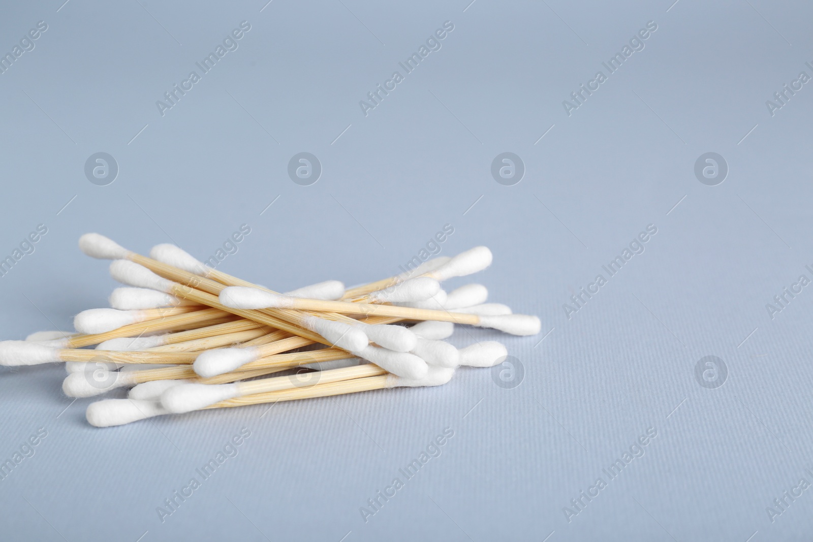 Photo of Wooden cotton buds on light grey background. Space for text