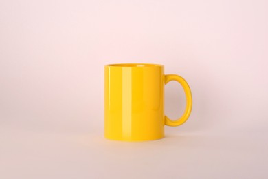 Photo of Blank yellow ceramic mug on light background