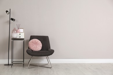 Photo of Comfortable armchair and decor near beige wall. Space for text