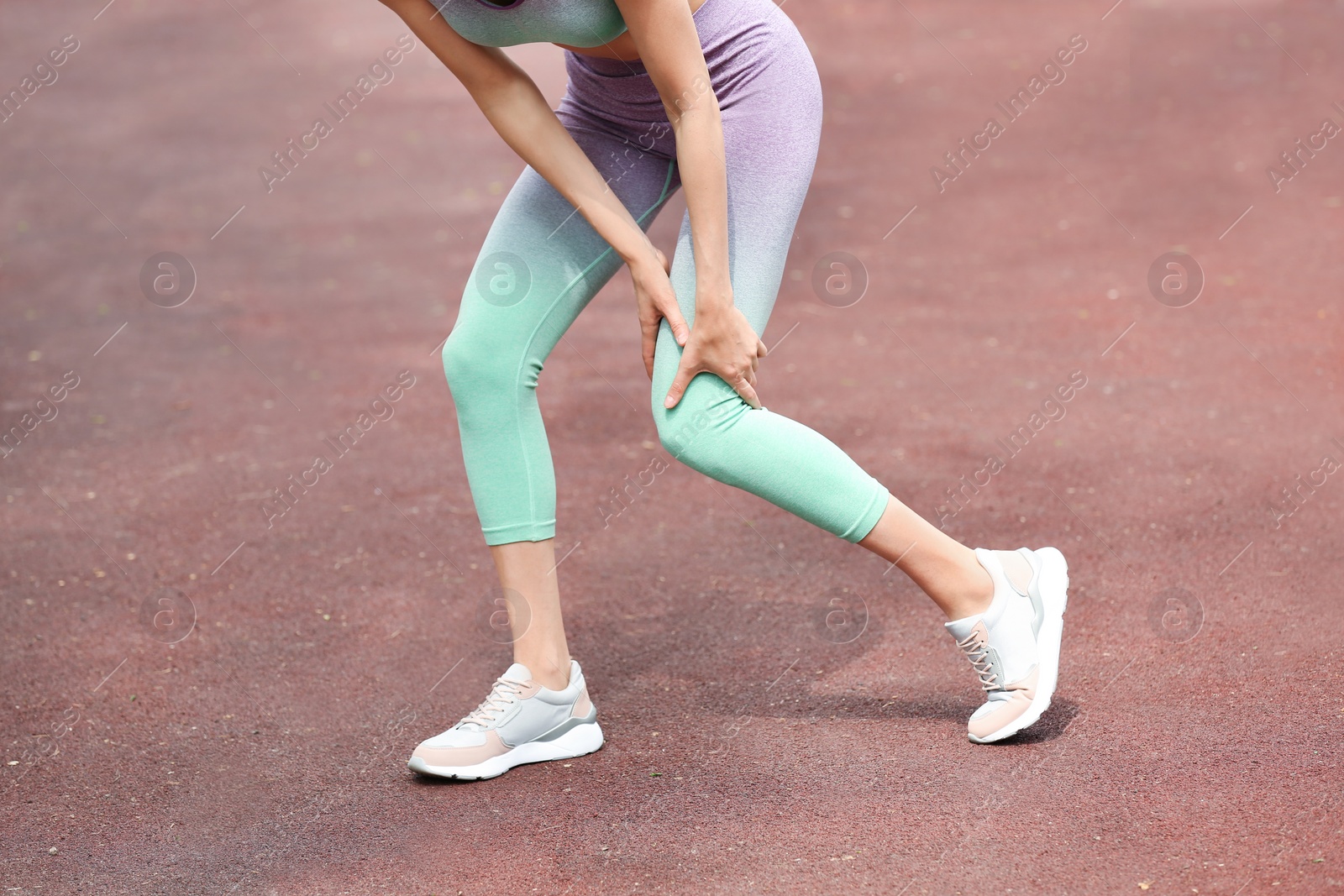 Photo of Young woman suffering from knee pain on sports ground, closeup