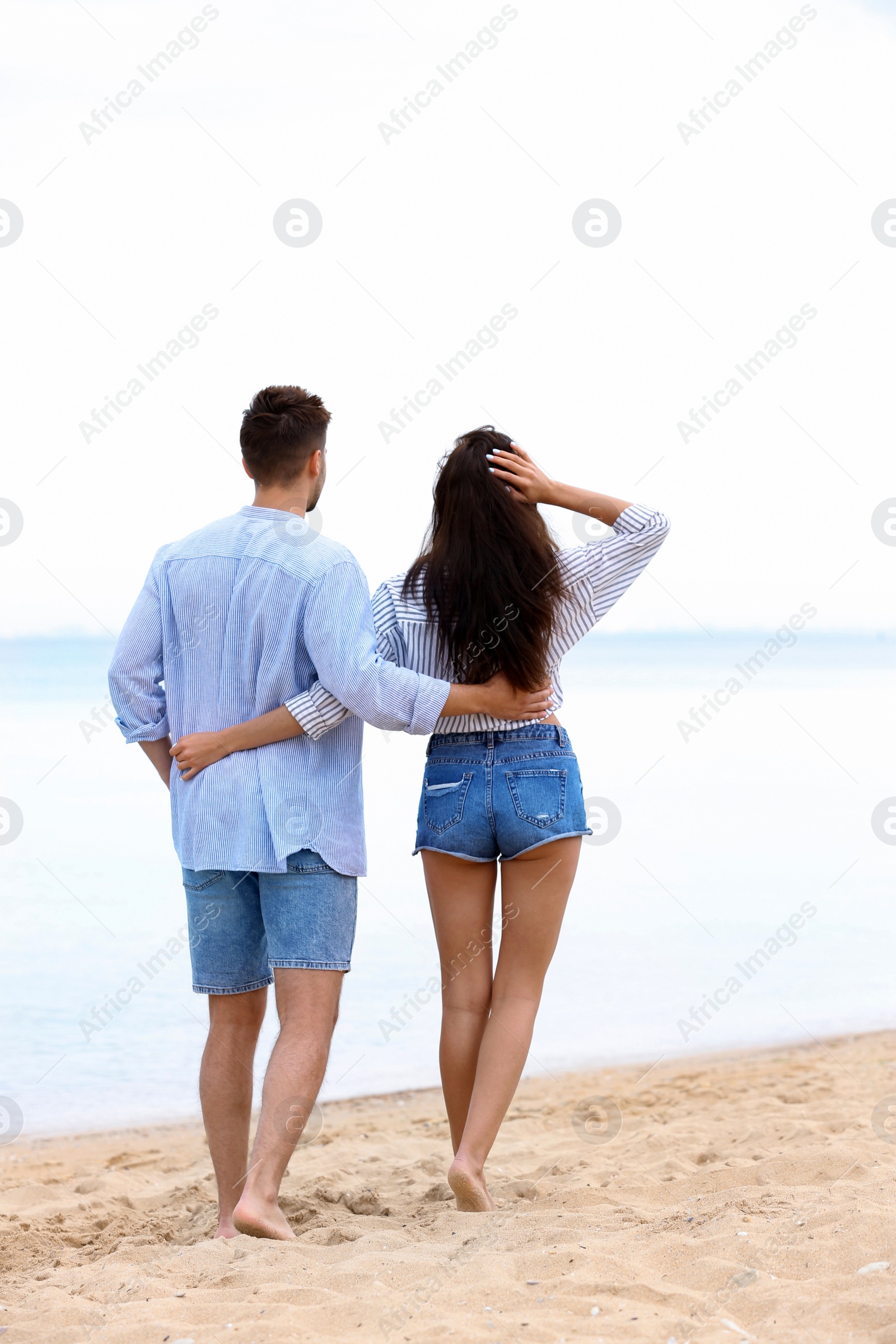 Photo of Happy young couple walking together on beach near sea