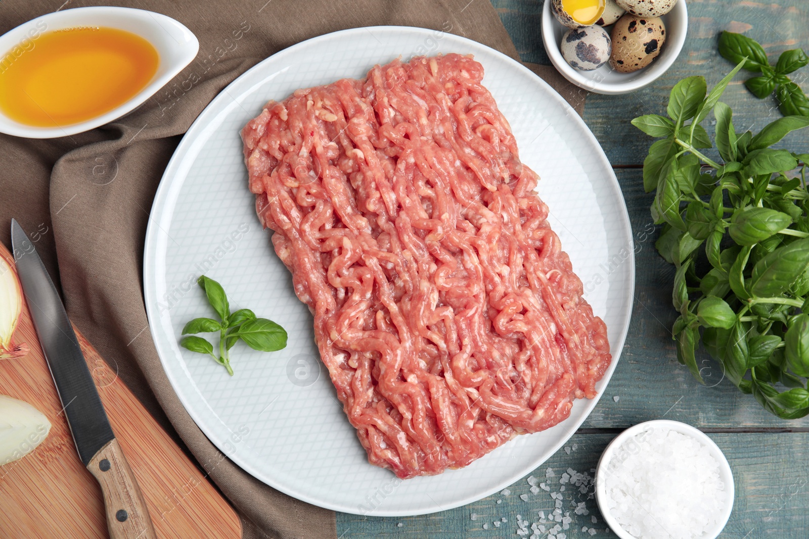 Photo of Raw chicken minced meat and ingredients on light blue wooden table, flat lay