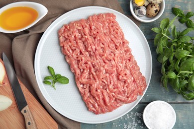 Raw chicken minced meat and ingredients on light blue wooden table, flat lay