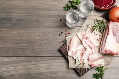 Photo of Tasty salt pork with rosemary and spices on wooden table, flat lay. Space for text