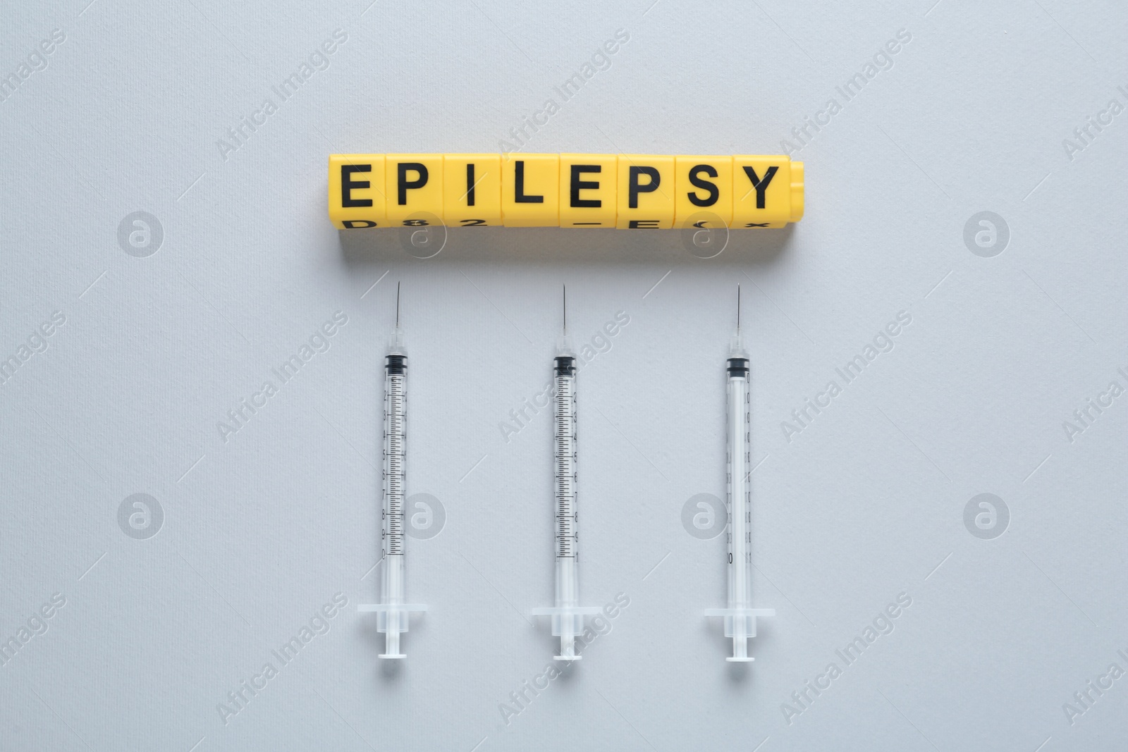 Photo of Blocks with word Epilepsy and syringes on light background, flat lay