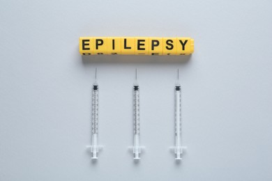 Photo of Blocks with word Epilepsy and syringes on light background, flat lay