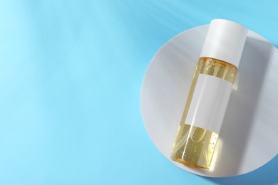 Photo of Bottle of cosmetic oil on light blue background, top view. Space for text